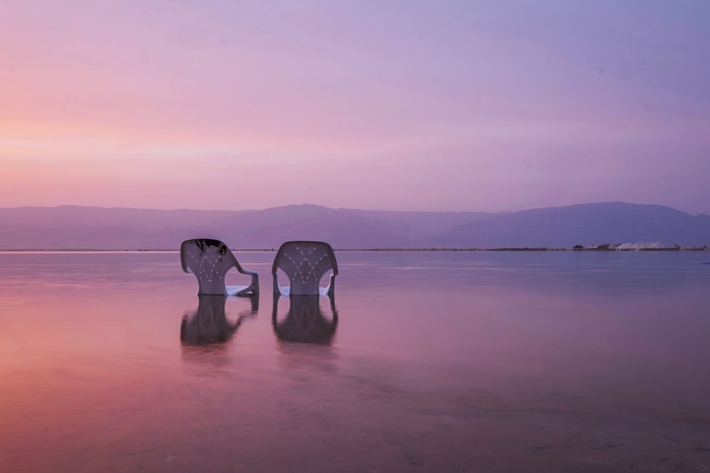 Zwei Stühle stehen am Strand im Wasser