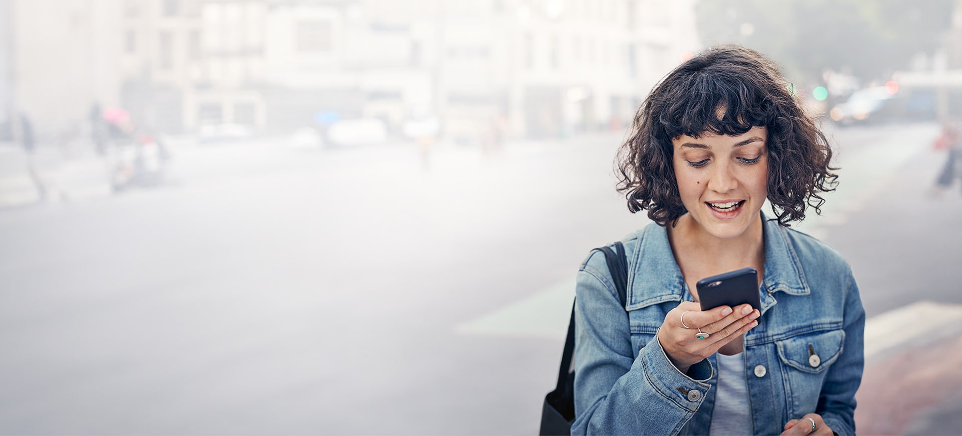 Junge Frau, die fröhlich auf ihr Smartphone schaut.