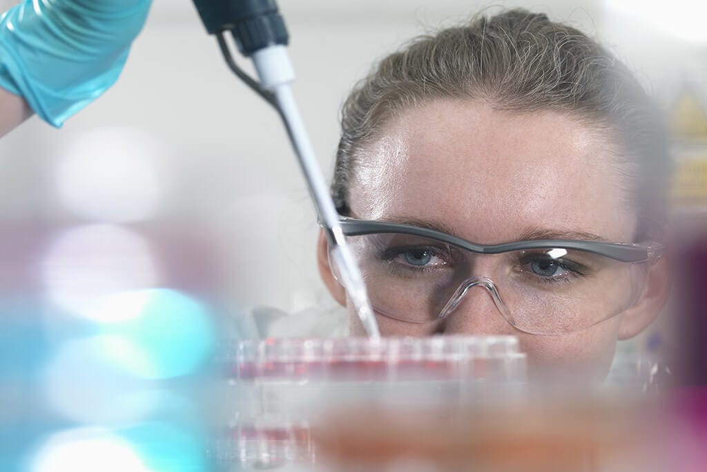 Eine Frau mit Schutzbrille arbeitet im Labor.