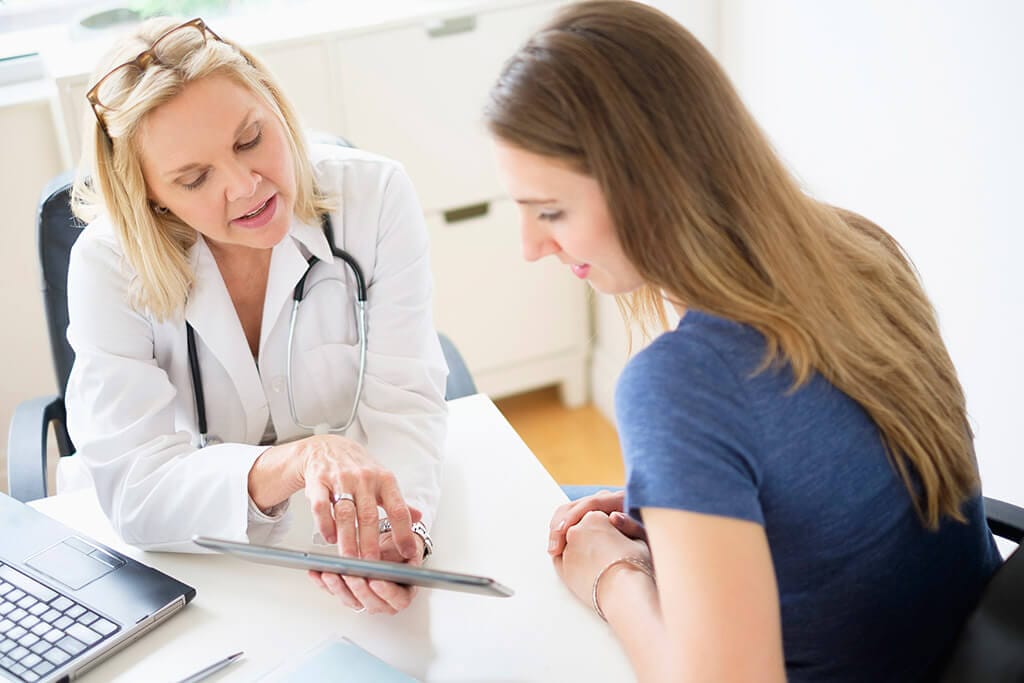 Eine Ärztin zeigt ihrer Patientin etwas auf einem Tablet.