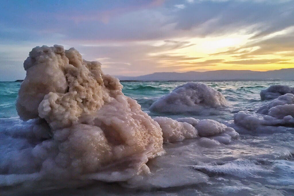 Das Meer bei Sonnenuntergang mit Salzsteinen im Vordergrund.