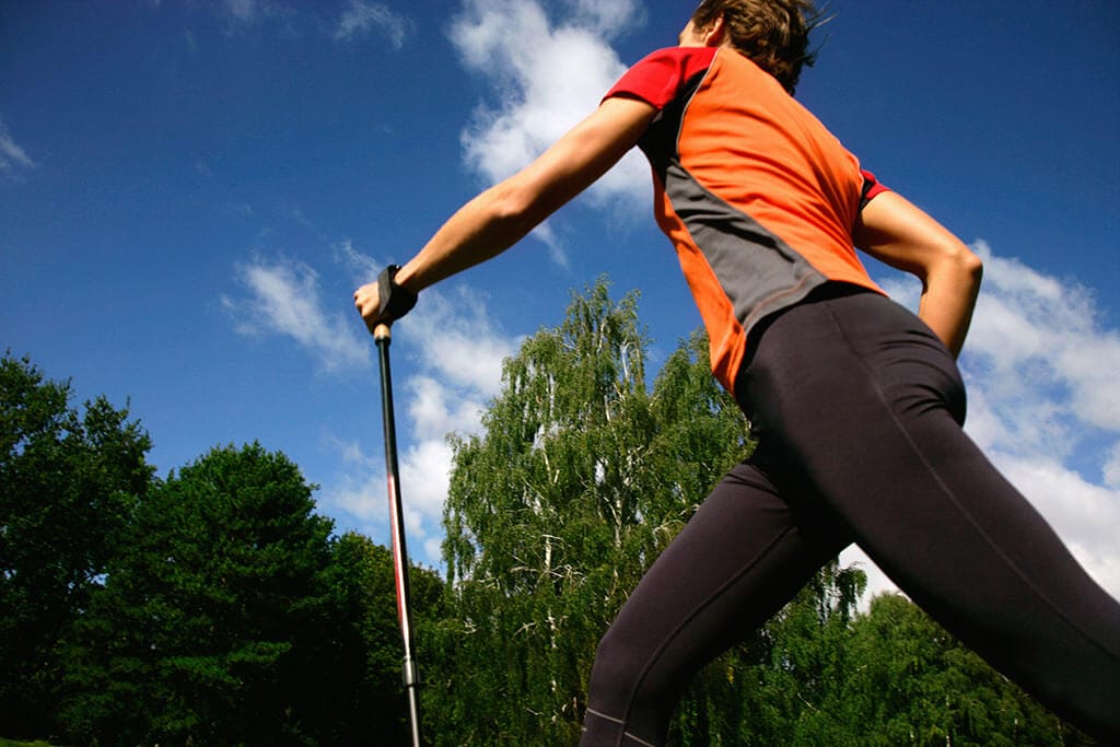Eine Frau macht Nordic Walking im Wald.
