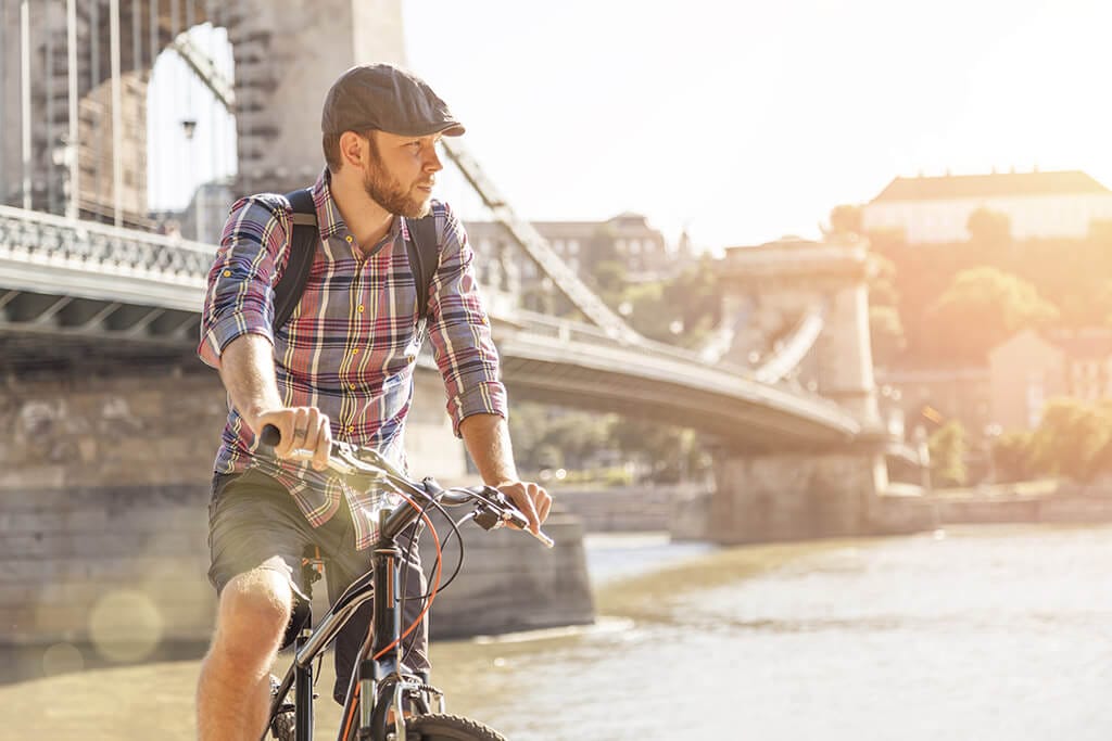 Ein junger Mann fährt mit seinem Fahrrad an einer Brücke