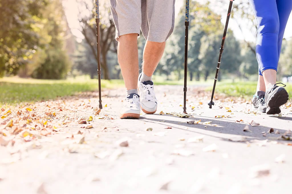 Die Beine von zwei Personen beim Nordic Walking.