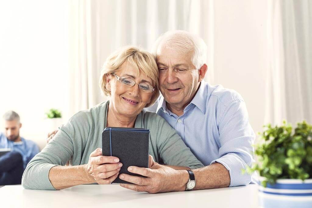 Älteres Paar schaut sich etwas auf einem Tablet an.