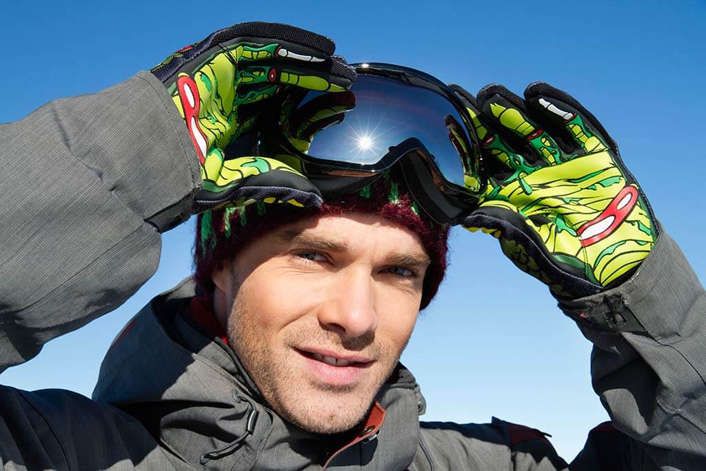 Ein Mann ein Skibekleidung zieht seine Skibrille an.