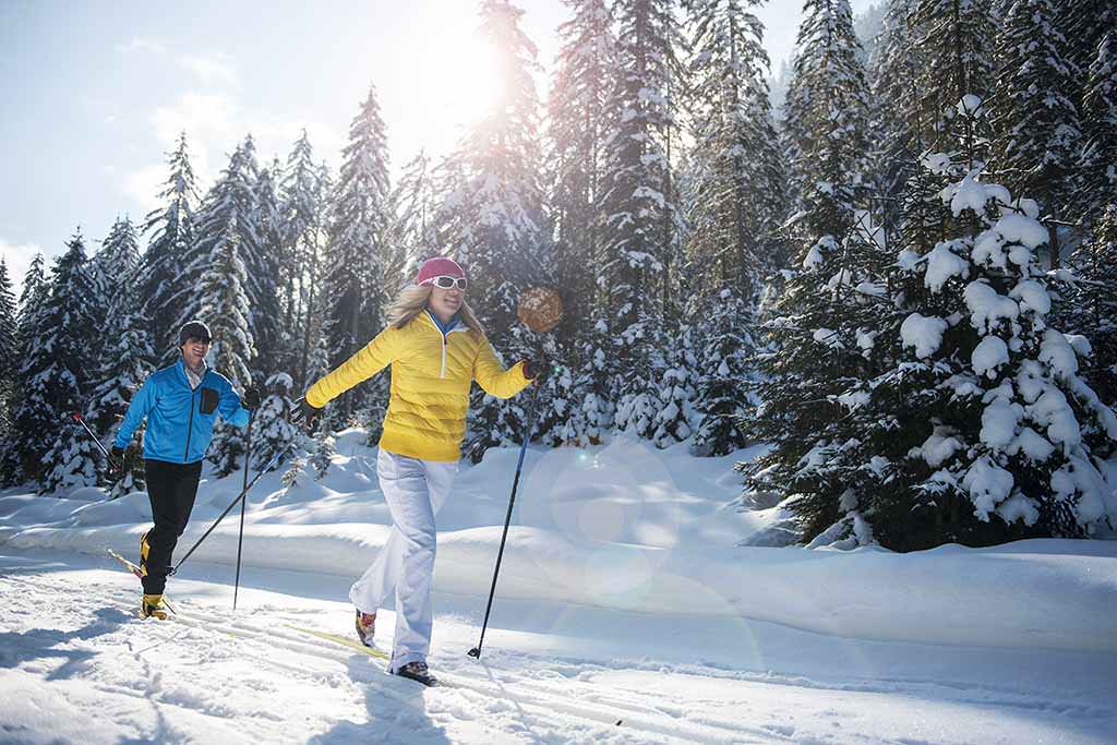 Zwei Personen beim Skilanglauf im Wald.