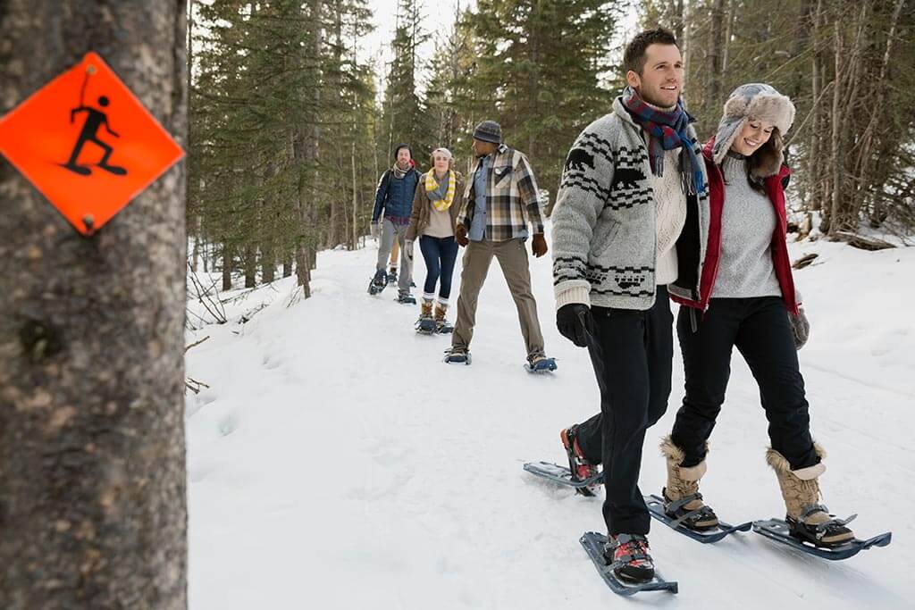 Eine Gruppe junger Menschen macht eine Schneeschuhwanderung.