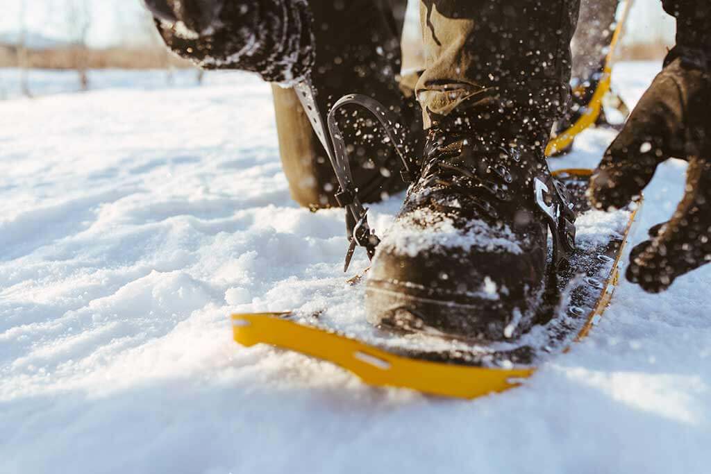 Eine Person zieht sich Schneeschuhe an.