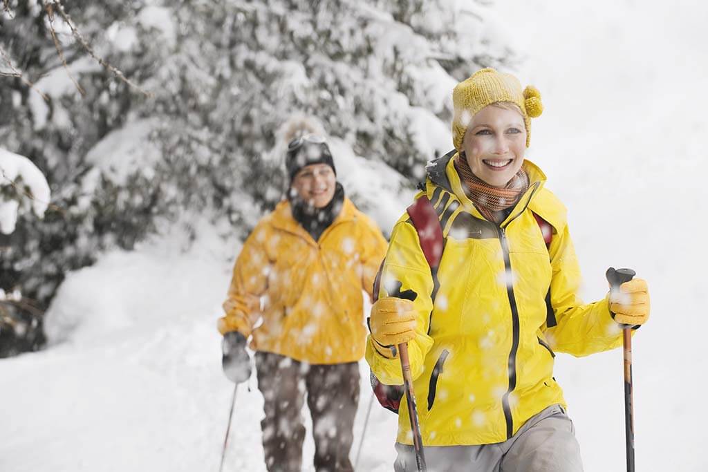 Ein Paar in gelber Kleidung wandern im Schnee.