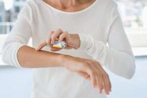 Frau cremt ihren Arm mit einer Salbe ein und hält die Tube in der Hand.