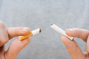 Vier Finger zerbrechen eine Zigarette.