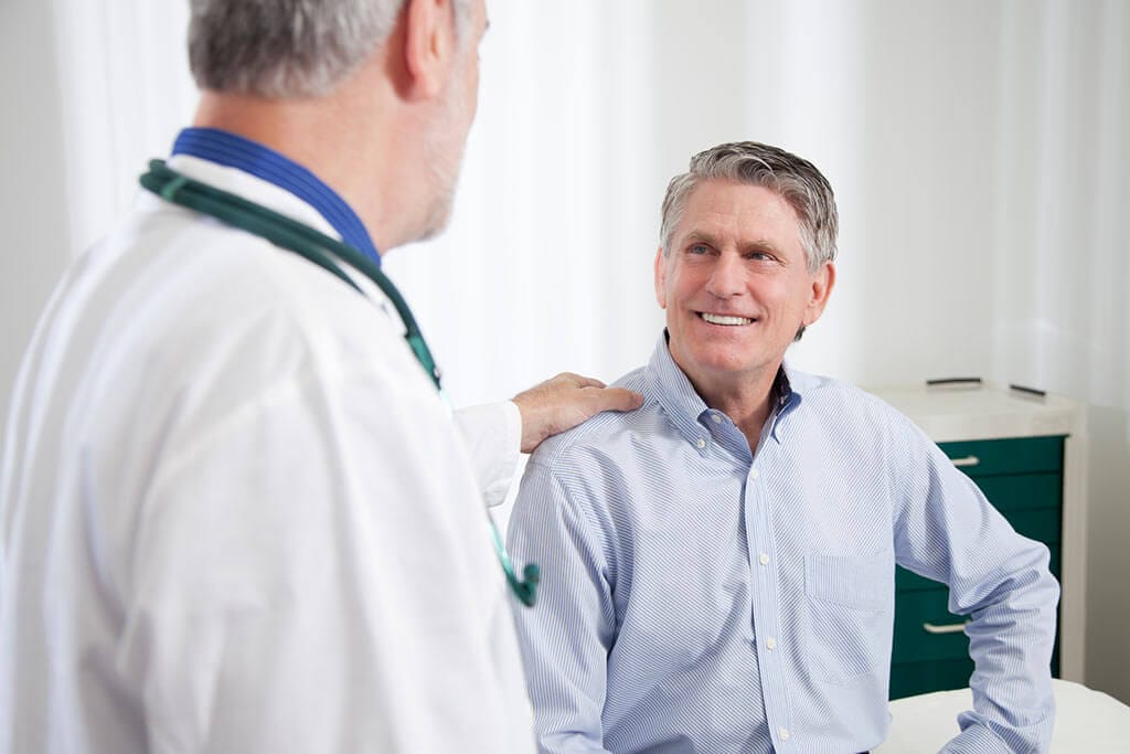 Ein Arzt legt seine Hand auf die Schulter eines Patienten.