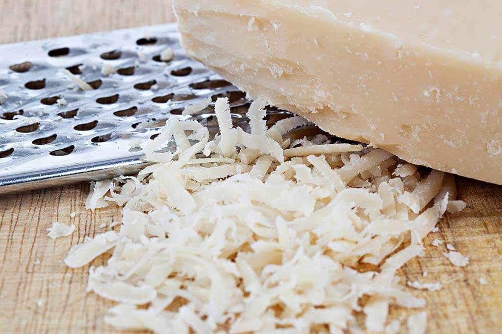 Geriebener Parmesankäse mit einer Reibe.