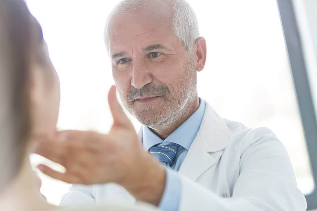 Ein Arzt begutachtet das Gesicht einer Patientin.