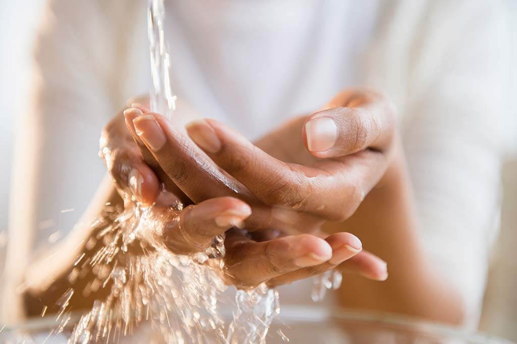 Eine Frau wäscht sich Ihre Hände unter Wasser.