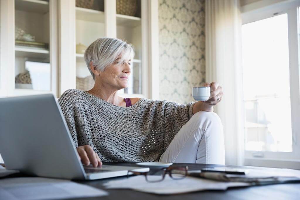 Frau mit Tasse schaut aus Fenster