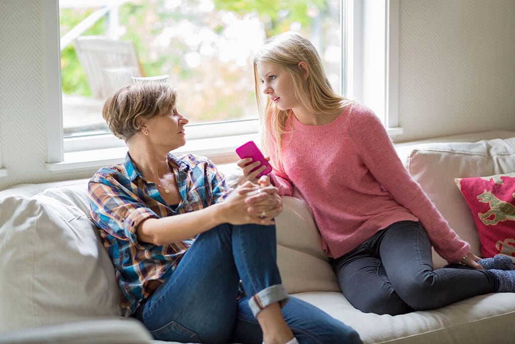 Eine Mutter sitzt mit Ihrer Tochter auf einem Sofa.