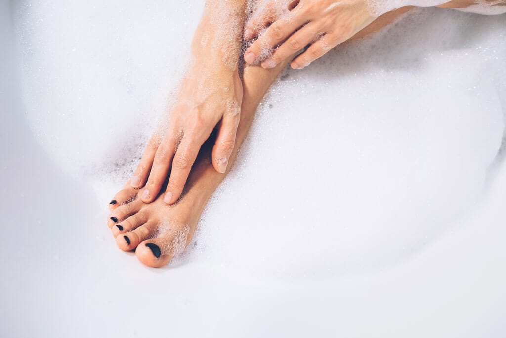 Frau pflegt ihre Füße in der Badewanne