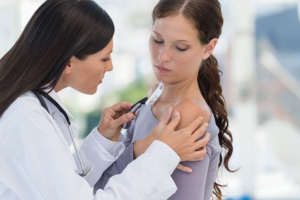 Eine Hautärztin untersucht eine Patientin an der Schulter.