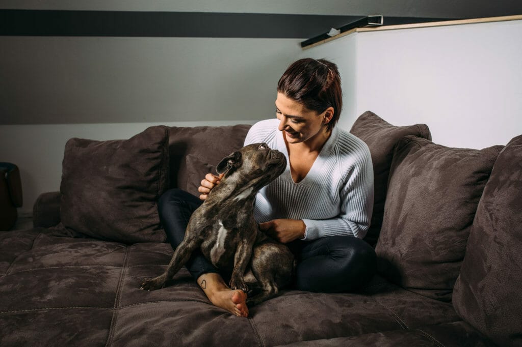 Germaine sitzt mit Ihrem hund auf dem Sofa.