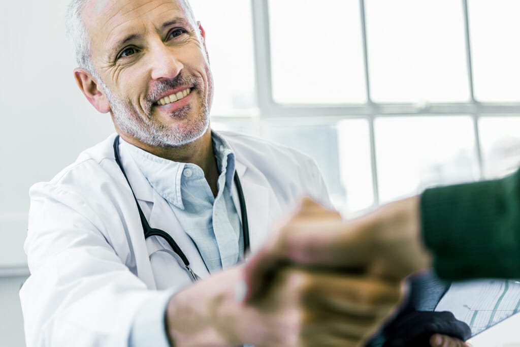 Ein Hautarzt reicht seinem Patienten die Hand