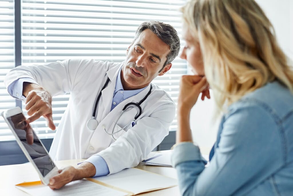 Ein Arzt zeigt seiner Patientin Therapiemöglichkeiten.