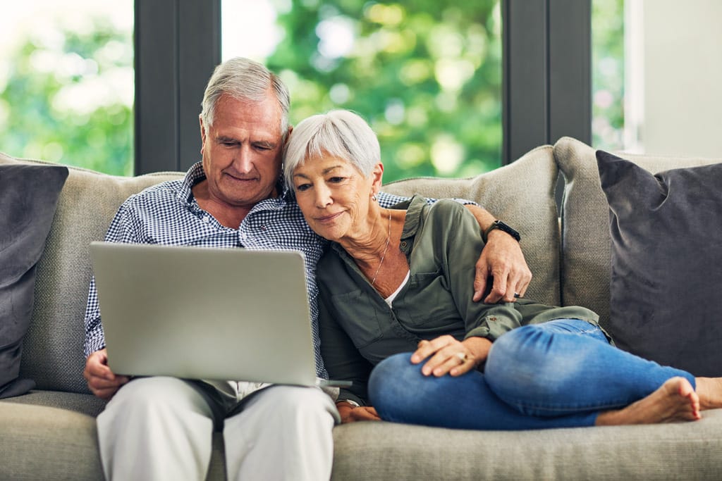 Älterer Mann mit Parkinson informiert sich auf dem Sofa