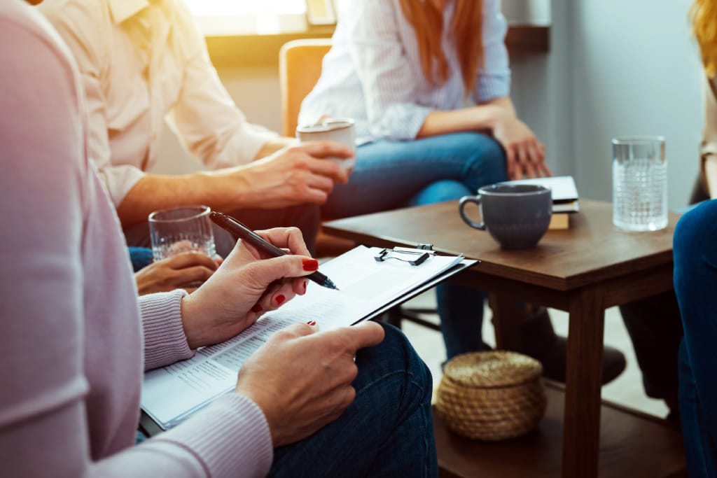 Mehrere Menschen im Gruppengespräch am Tisch