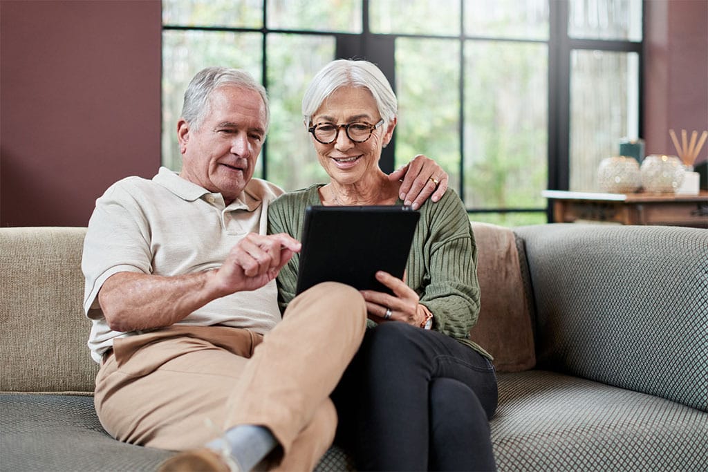 Älteres Ehepaar informiert sich am Tablet über Blutkrebs