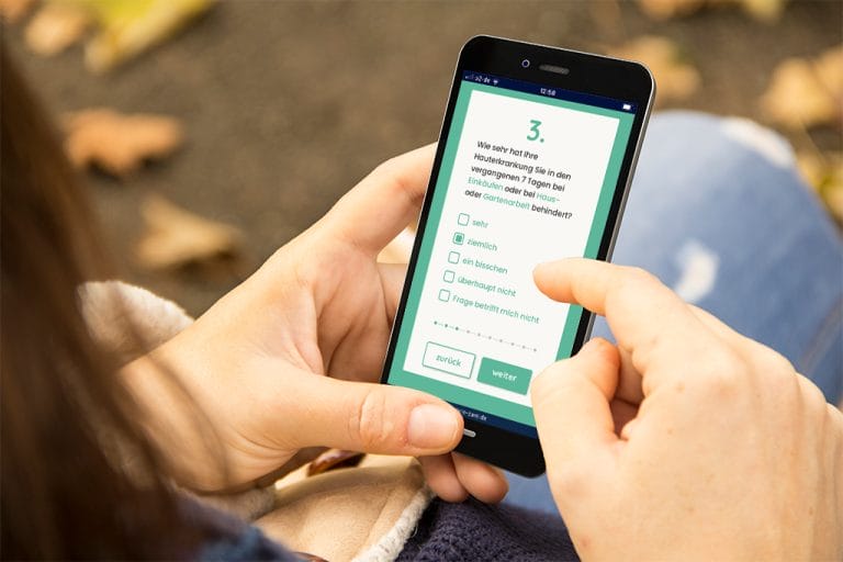 Eine Frau füllt den DLQI-Test am Handy aus.