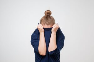 Frau versteckt ihr Gesicht im Pullover