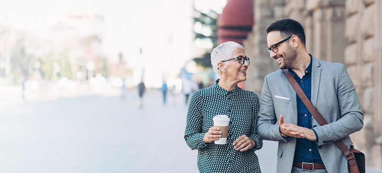 Eine Frau und ein Mann in Business Klamotten laufen durch die Stadt