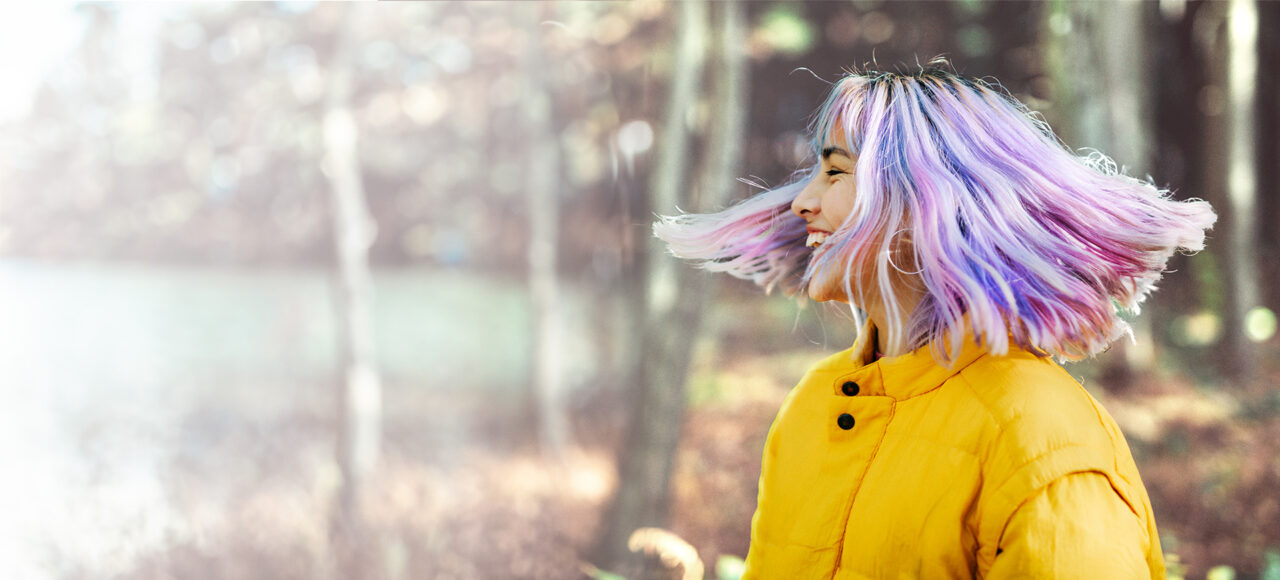 Ein Teenie mit bunten Haaren und Nuerodermitis ist im Wald spazieren