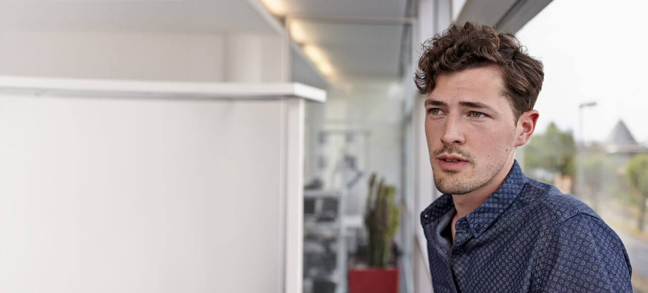 Ein junger Mann mit Locken und Schuppenflechte schaut in die Ferne