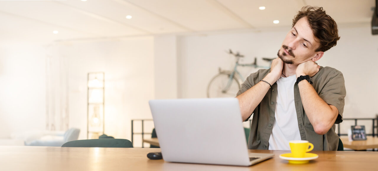 EIn junger Mann trinkt einen Espresso und informiert sich am Laptop über Uveitis