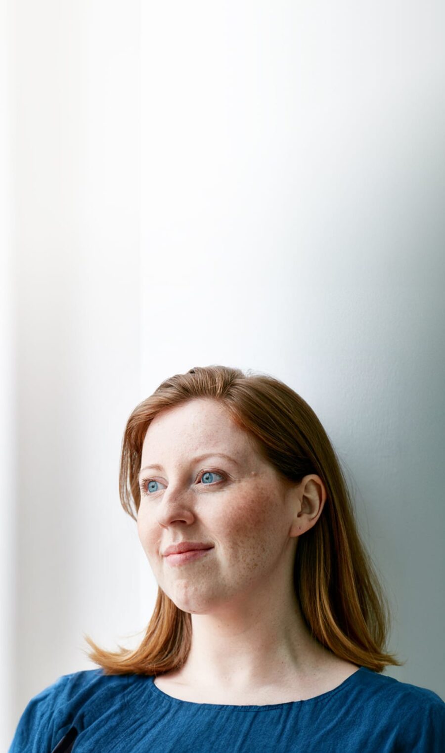 Eine rothaarige Frau schaut in die Ferne.