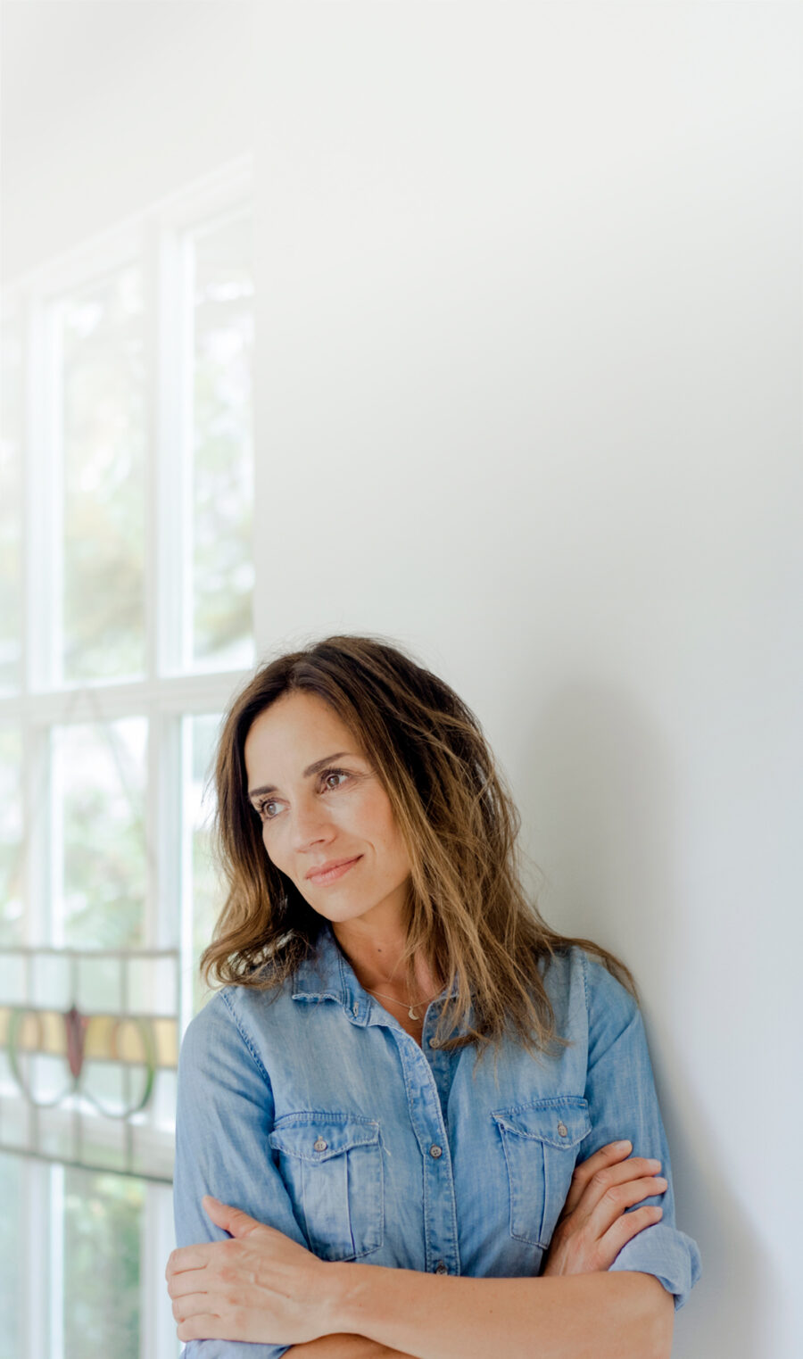 Eine Frau mit rheumatoider Arthritis in einem Jeans-Hemd lehnt sich gegen die Wand