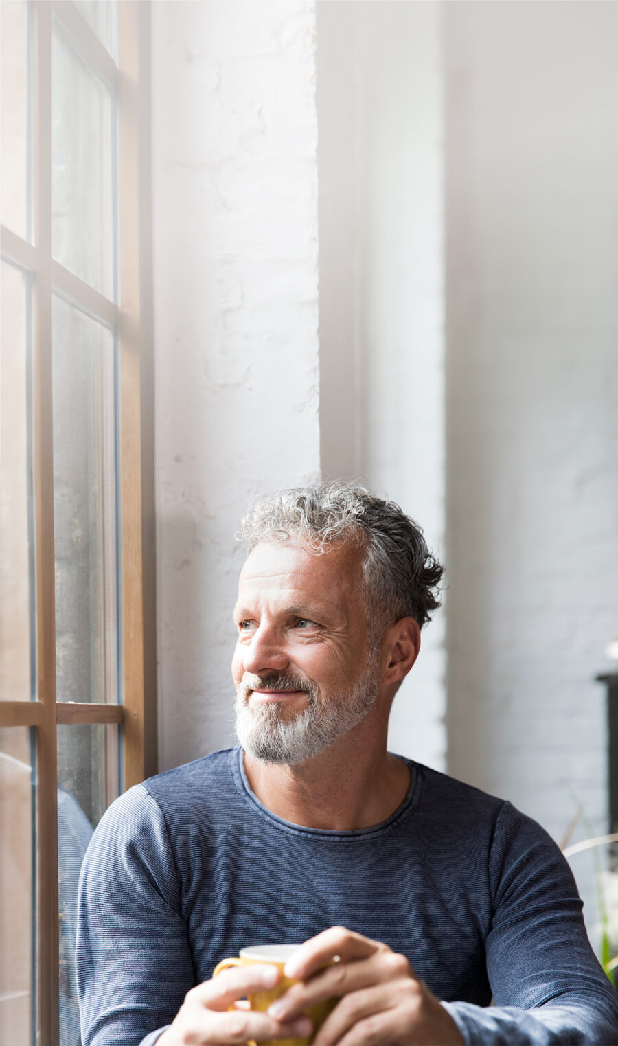 Ein Mann mit Rheuma trinkt einen Kaffee am Fenster