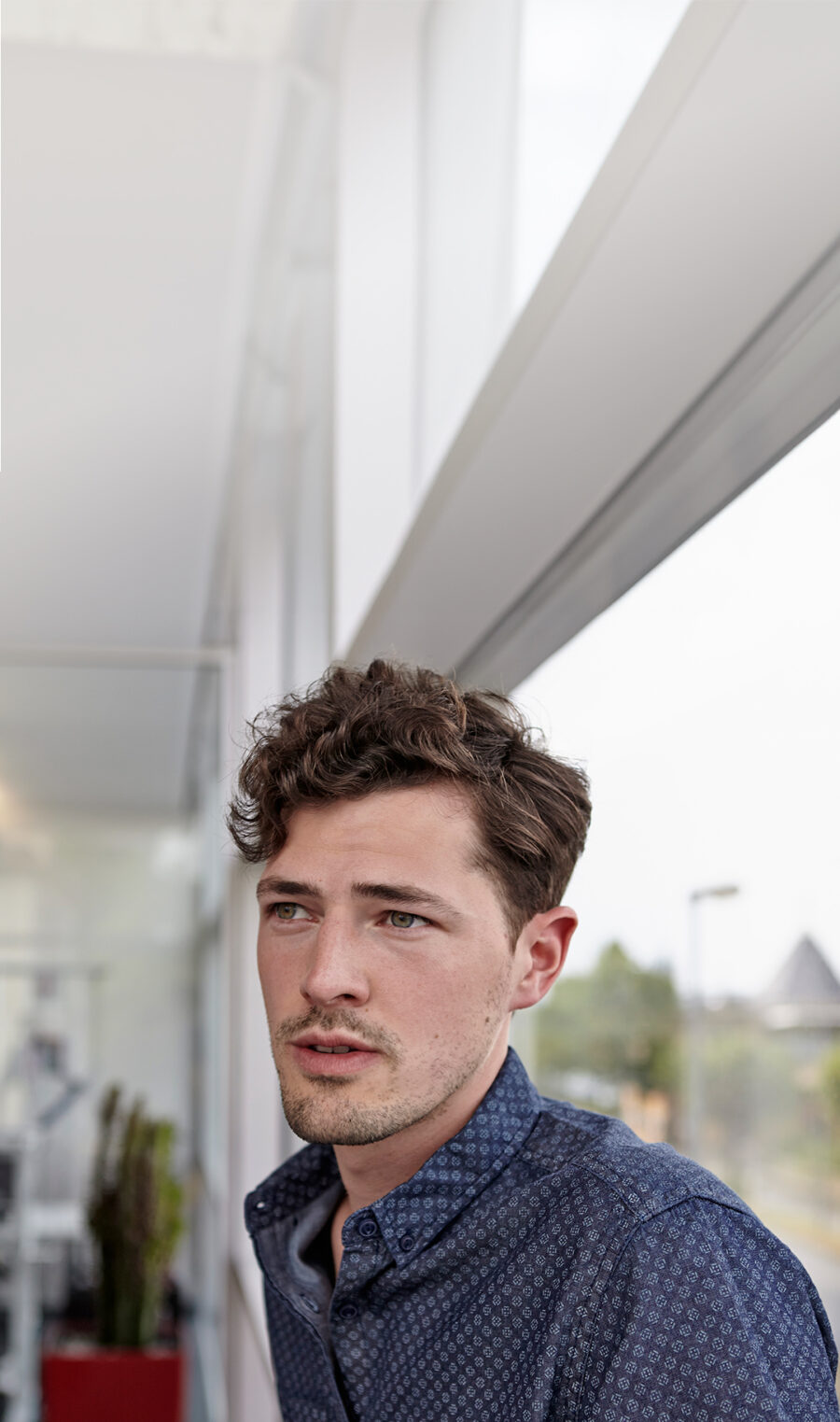 Ein junger Mann mit Locken und Schuppenflechte schaut in die Ferne