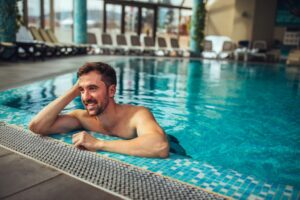 Mann am Beckenrand im Schwimmbad