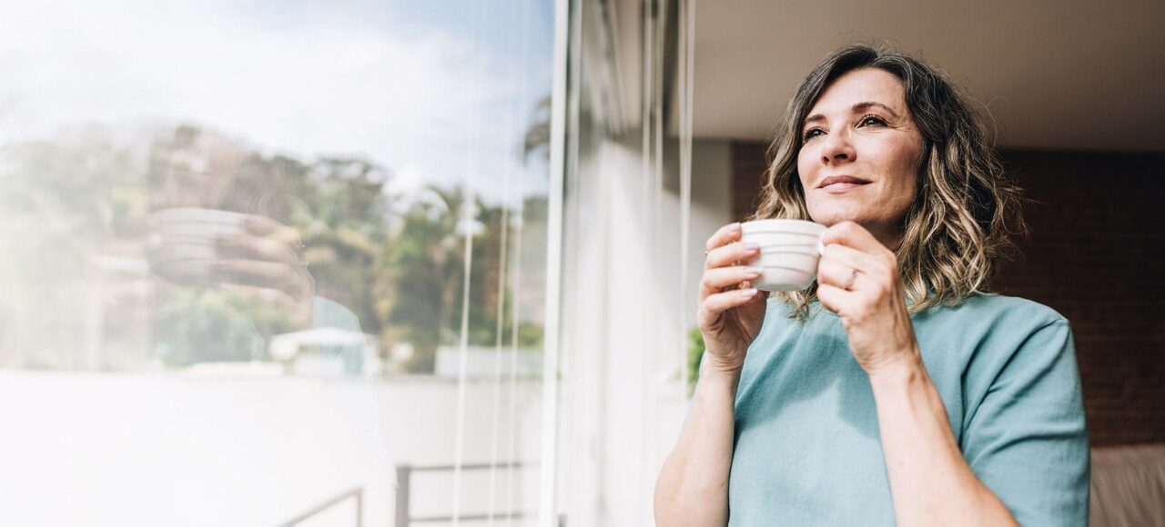 Frau trinkt Kaffee am Fenster