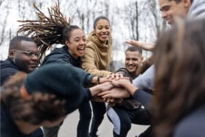 Mehrere junge Leute stehen lachend im Kreis und schlagen die Hände aufeinander
