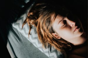 Frau mit Migräne liegt mit geschlossenen Augen auf der Couch