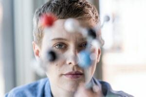 Eine Frau mit Migräne und kurzen braunen Haaren blickt auf Atommodel