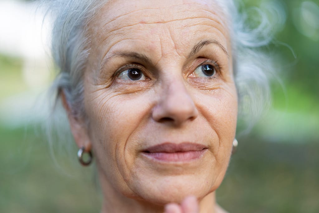 Frau mit grauen Haaren schaut in die Ferne