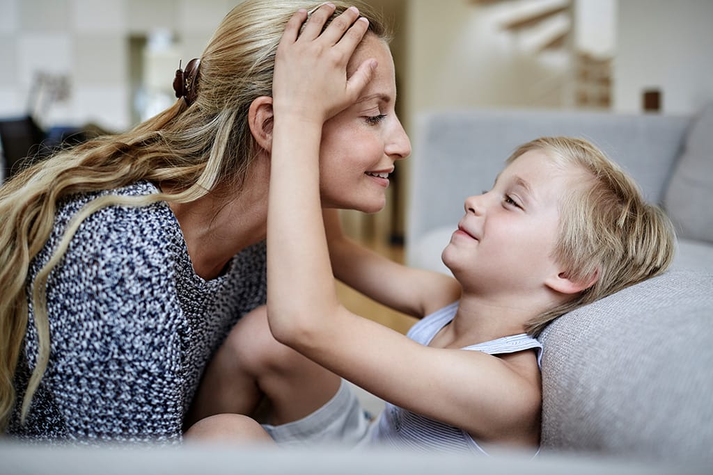 Mutter kuschelt mit ihrem Sohn im Wohnzimmer