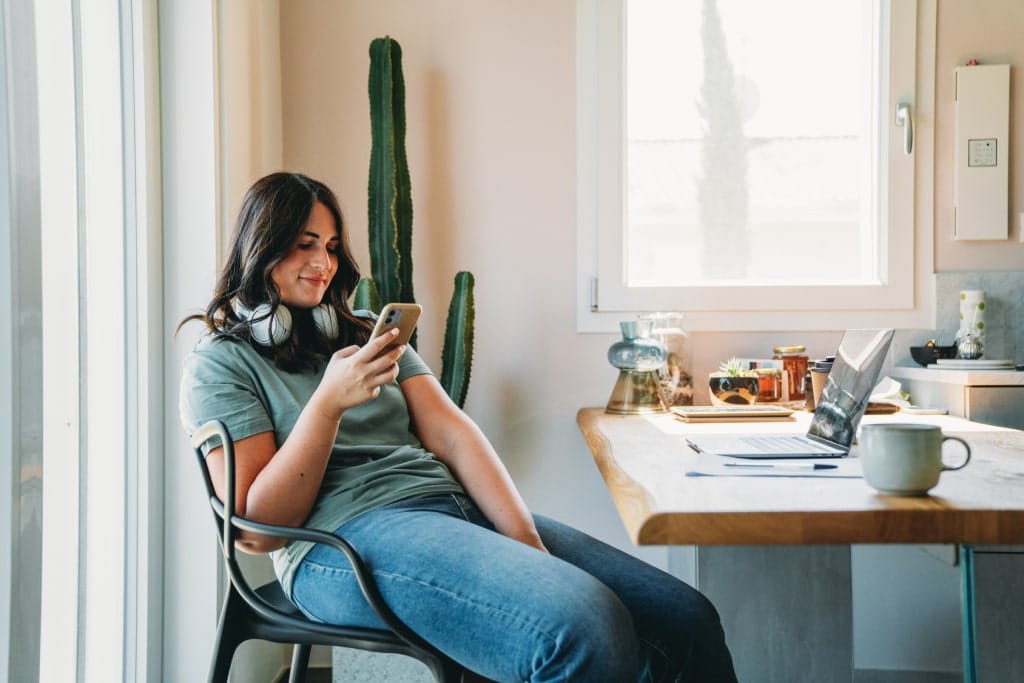 Junge Frau schaut sich ein Webinar am Handy an