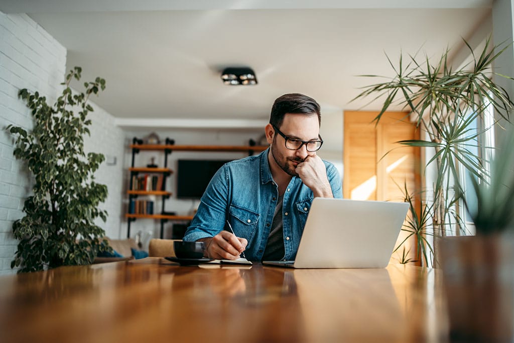 Mann mit Brille sitzt am Laptop und informiert sich über Rheuma