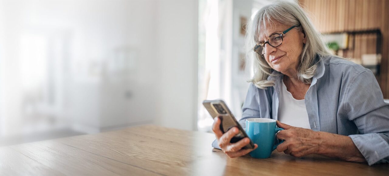 Frau mit grauen Haaren und einer Kaffeetasse in der Hand informiert sich über Riesenzellarteriitis